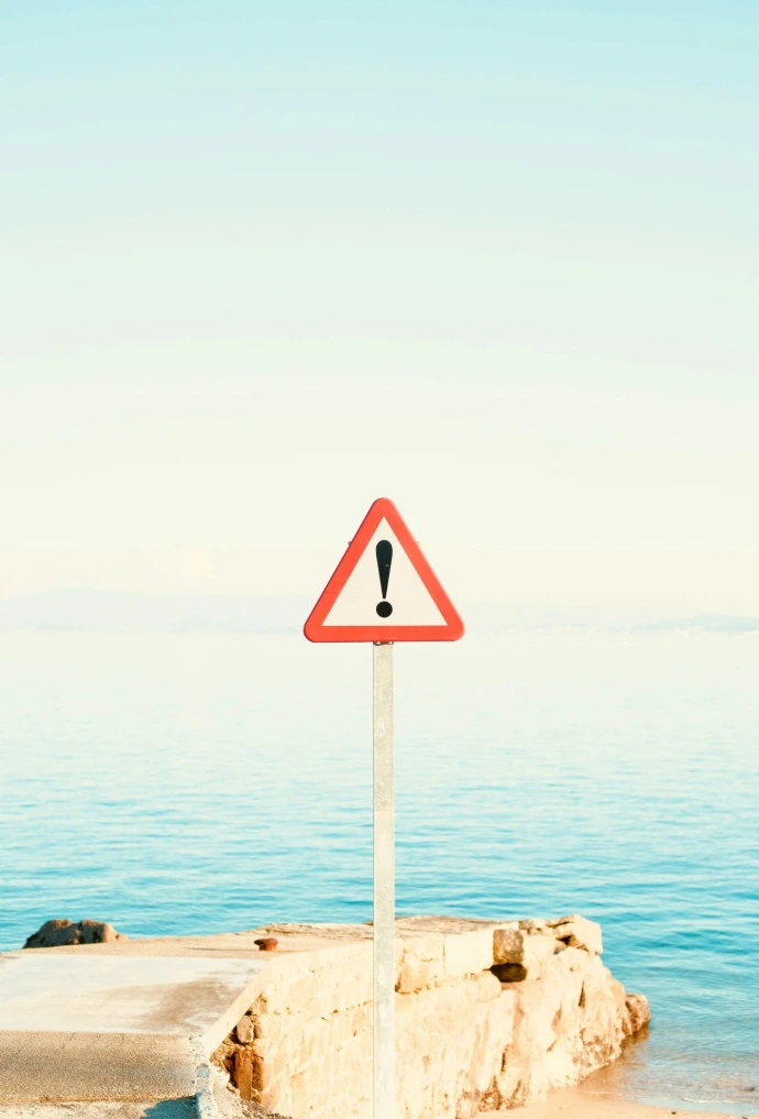Warning sign on a pier by the ocean